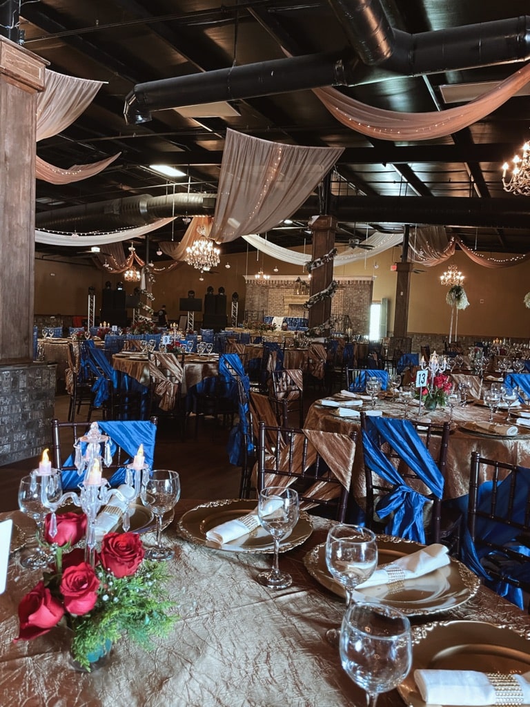 Event Venue Gainesville GA Banquet hall at La Hacienda event venue Gainesville GA with gold linens, blue napkins, chandeliers, and ceiling drape