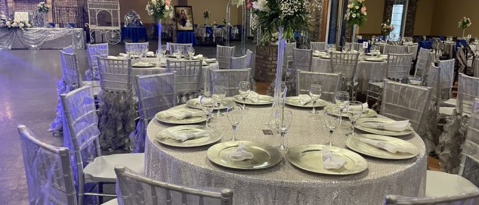 Reception table at a Gainesville, GA wedding venue with tall floral centerpiece, silver Chiavari chairs, and draped ceilings